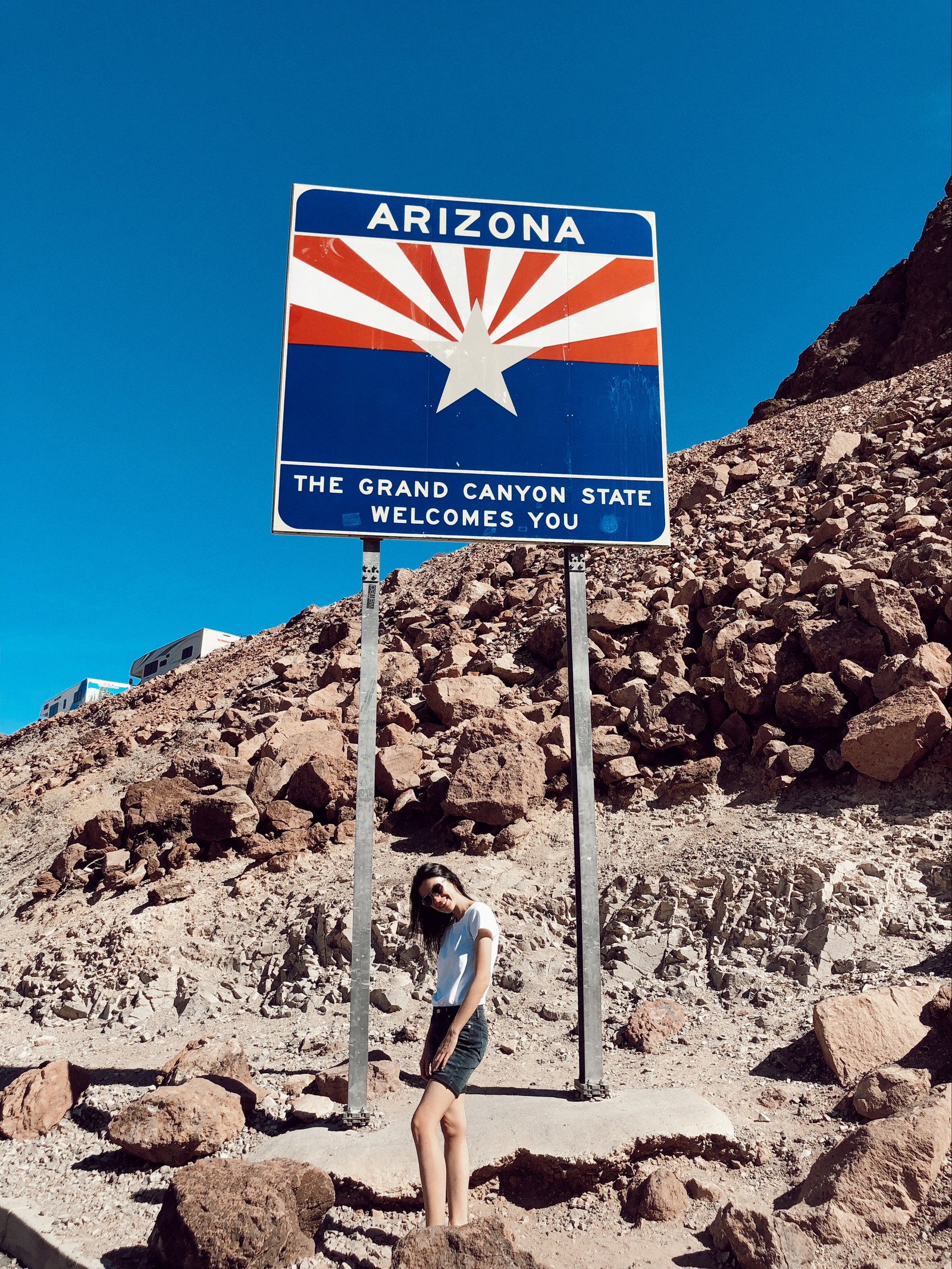 Uma mulher em pé em frente a uma placa no deserto (arizona, nevada, viagem, cadeia de montanhas, turismo)