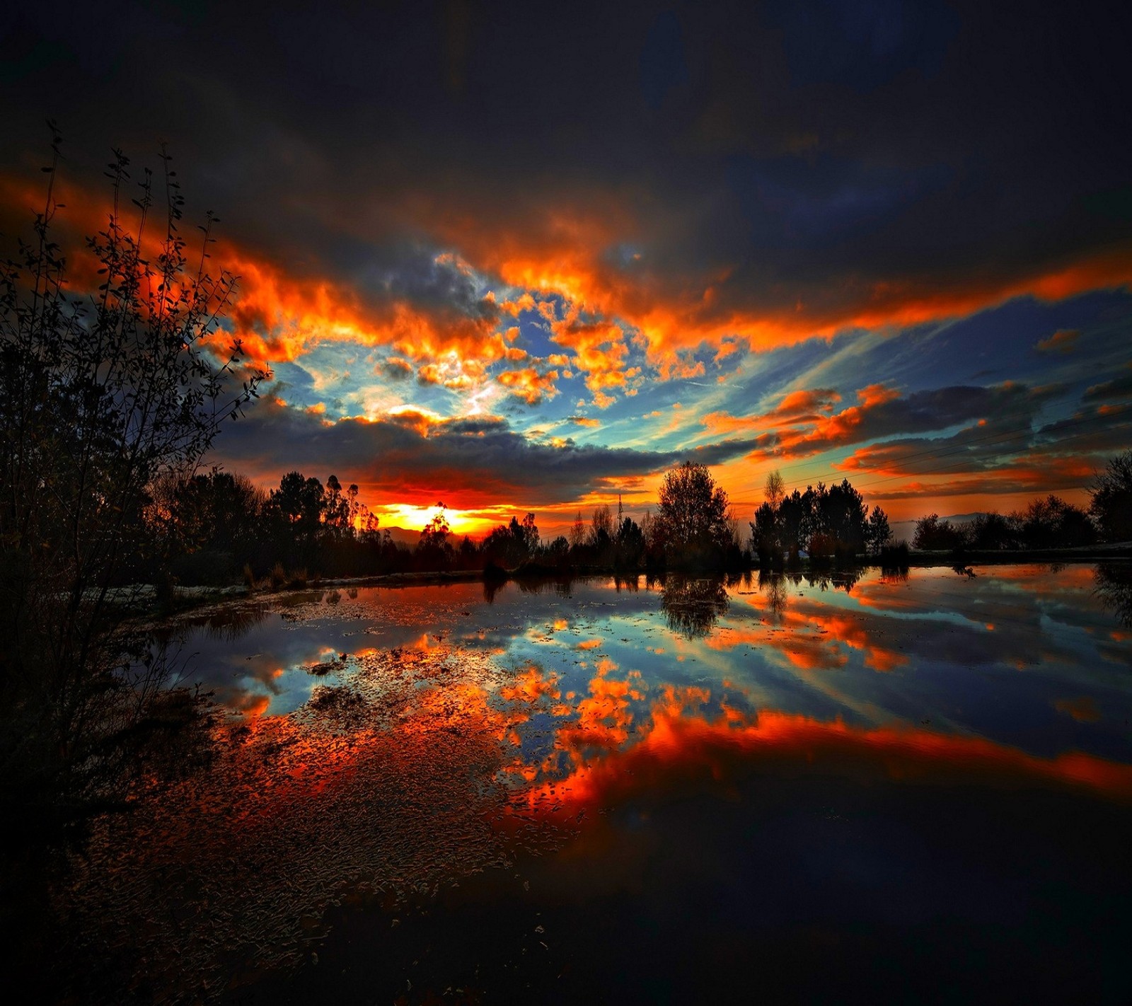 Un coucher de soleil sur un lac avec un reflet d'arbres et de nuages (nuages, soir, ciel, coucher de soleil, crépuscule)