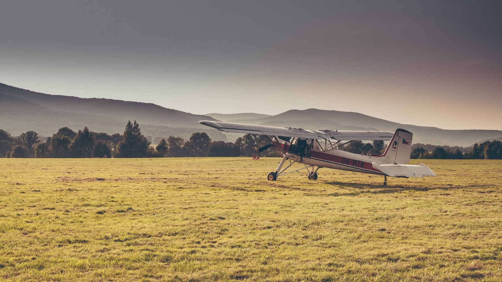 Ein arabisches flugzeug sitzt auf einem feld mit bergen im hintergrund (flugzeug, luftfahrt, allgemeine luftfahrt, flug, berge)