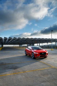 Jaguar I-PACE dans un parking moderne sous un ciel dramatique.