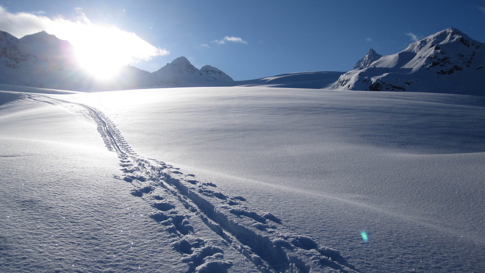 Vista aérea de rastros na neve com o sol brilhando atrás deles (montanha, neve, forma glacial, inverno, cadeia de montanhas)