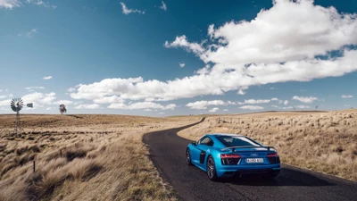 Audi R8 на извивающейся дороге под голубым небом, окруженный открытым ландшафтом.