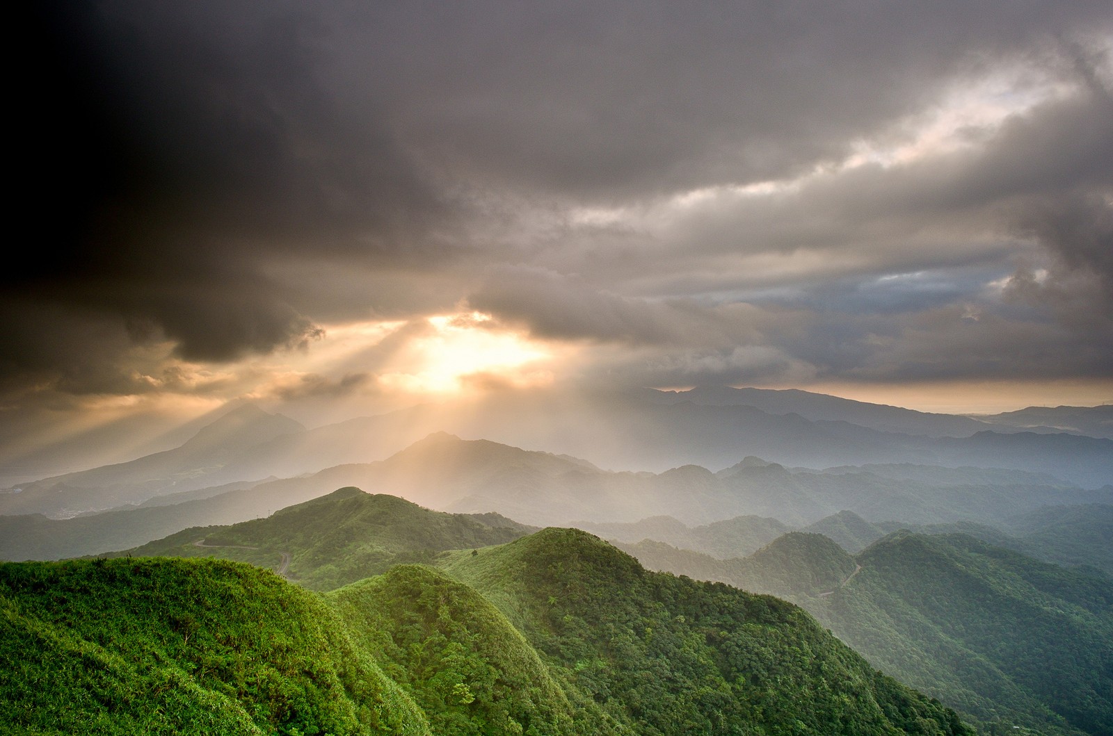 A view of a mountain range with a sunbeam in the sky (nature, highland, hill, cloud, atmosphere)