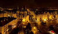 Praça Velha iluminada à noite com igreja e reflexos da paisagem urbana