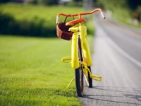 Helles gelbes Fahrrad, das am Wegesrand einer Wiese ruht