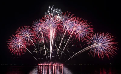 Spectacle de feux d'artifice vibrant reflété dans l'eau au réveillon du Nouvel An