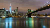 Nighttime Skyline of New York City with Illuminated Skyscrapers and a Bridge Reflection