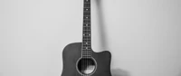 Black and white image of an acoustic guitar against a plain background.