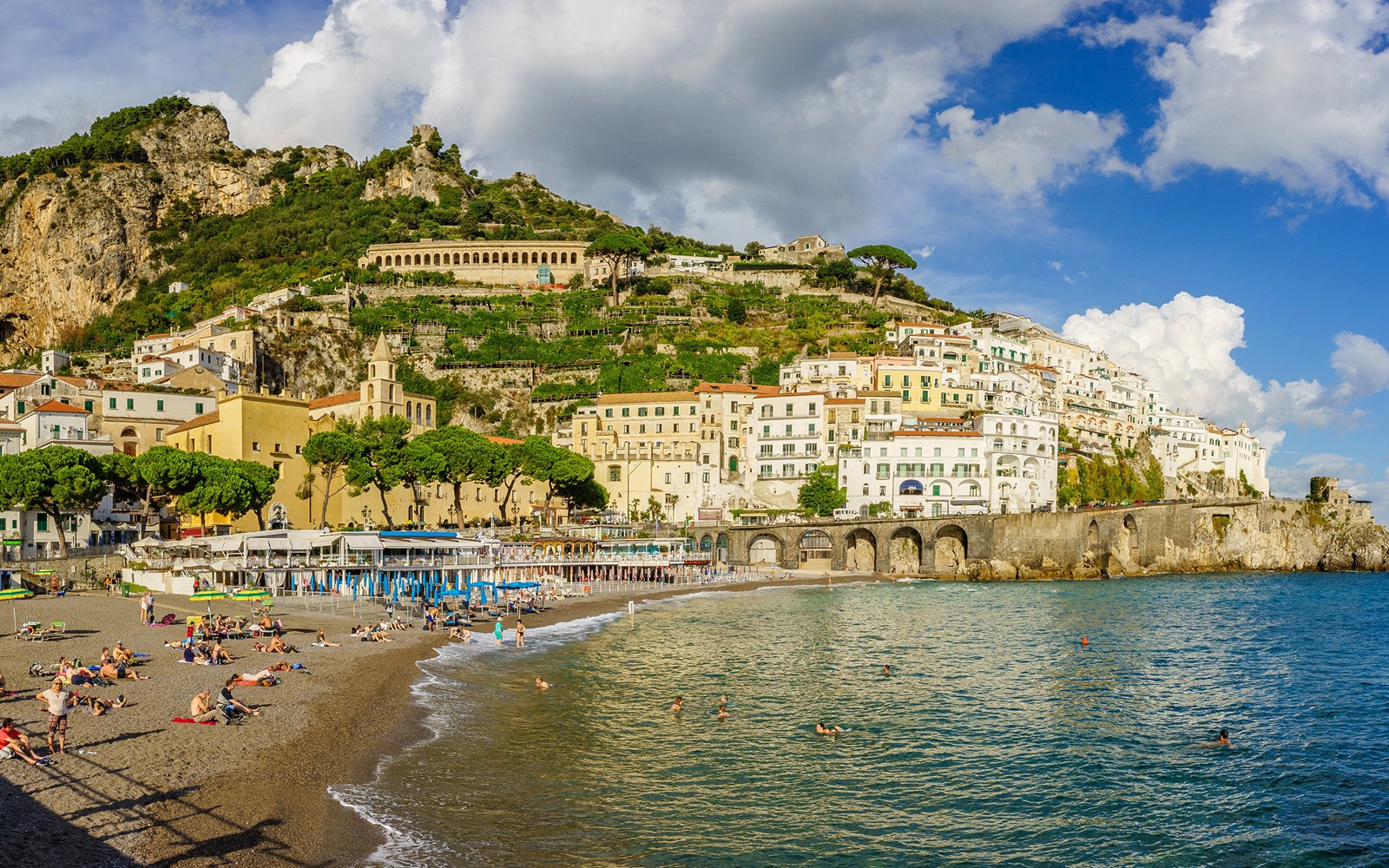 Uma vista de uma praia com uma colina ao fundo (sorrento, positano, cidade, costa, mar)