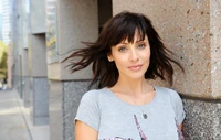 Beautiful lady with layered brown hair, showcasing a radiant smile and effortless style against an urban backdrop.