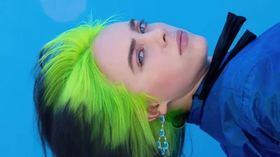 Billie Eilish avec des cheveux verts frappants et un fond bleu dans une séance photo captivante.