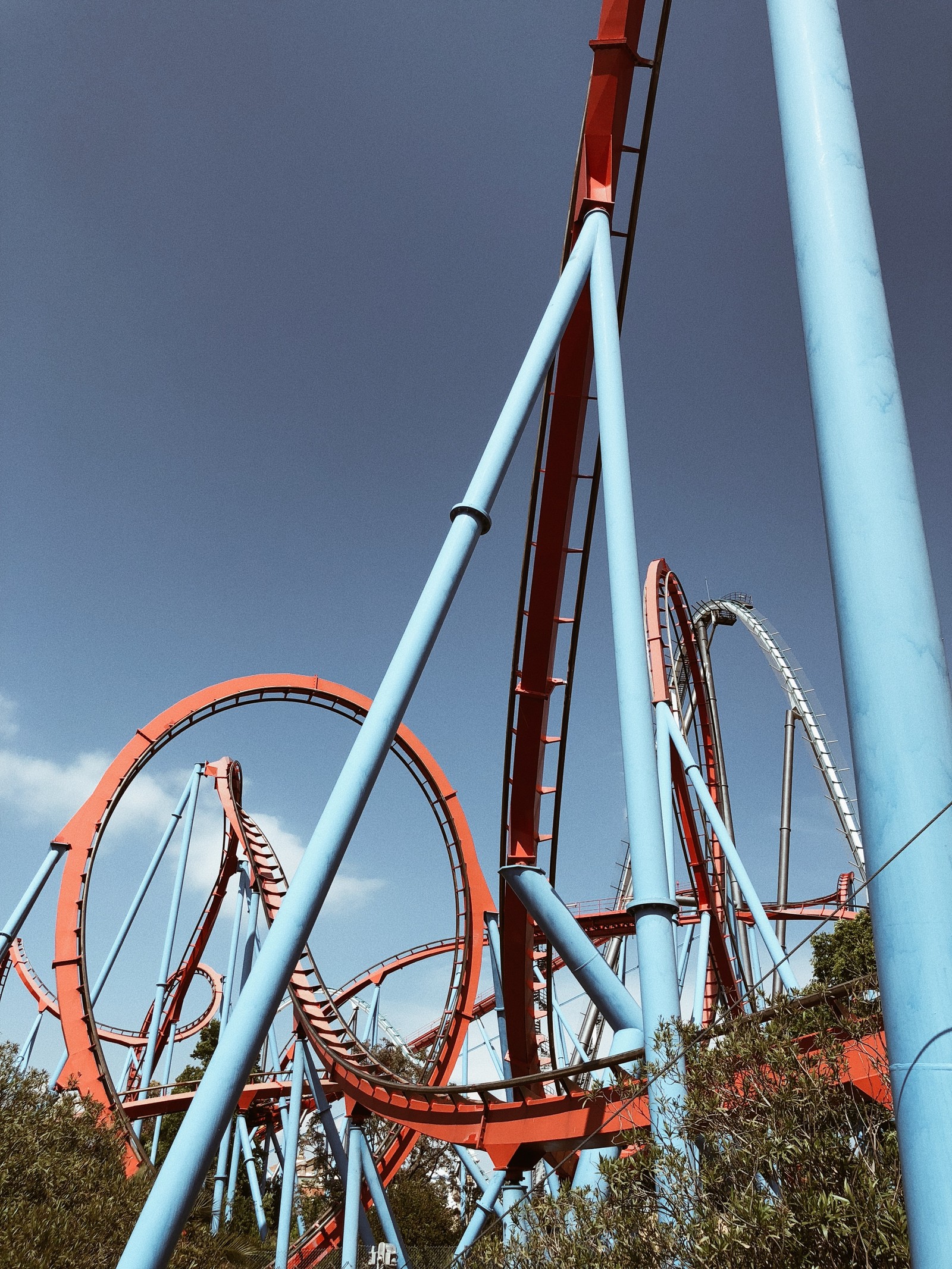 There is a man riding a roller coaster in a park (tourist attraction, amusement park, nature, daytime, bicycle frame)