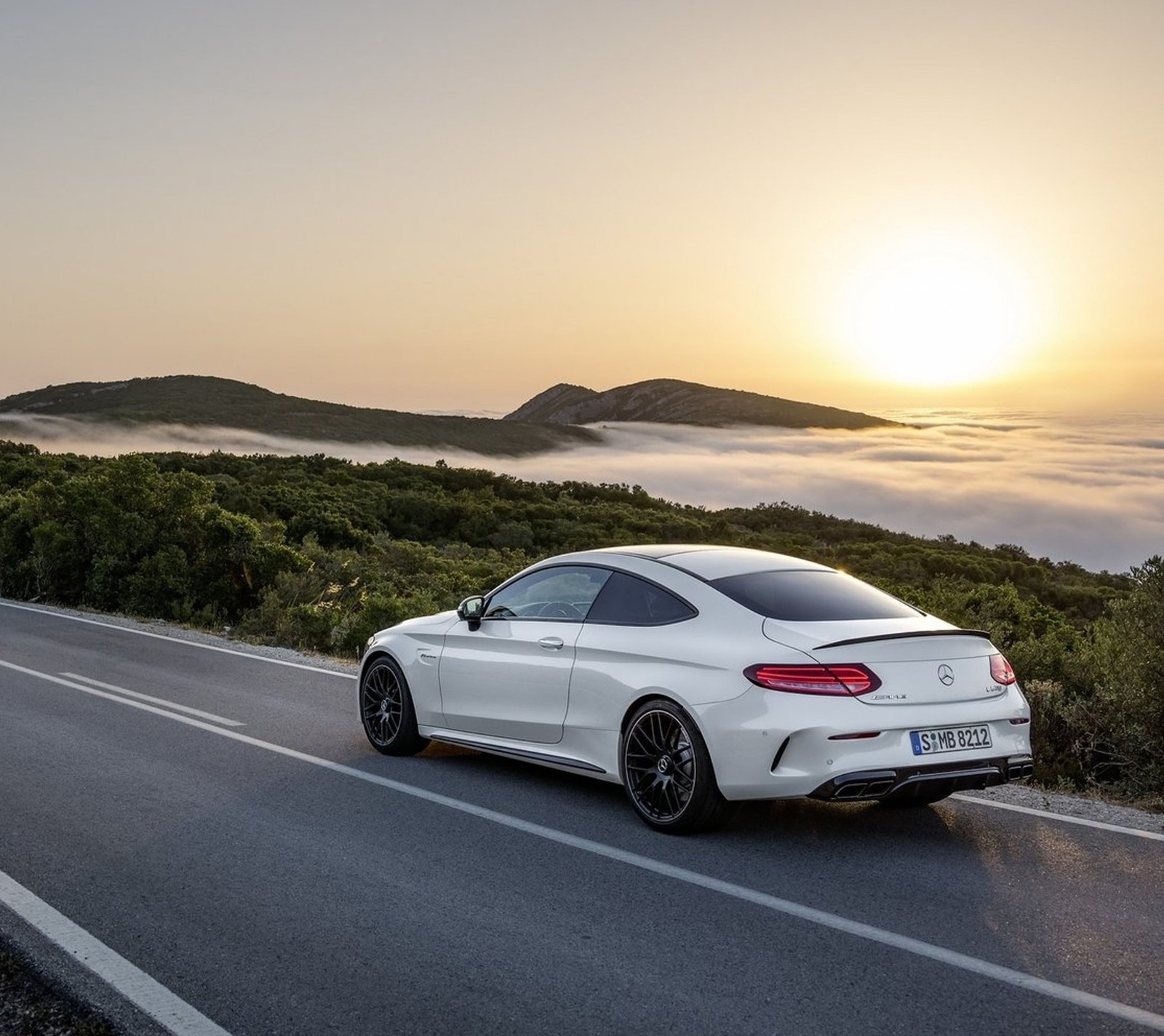 Um coupé mercedes branco dirigindo por uma estrada com um pôr do sol ao fundo (amg, benz, carro, mercedes)