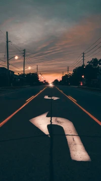 Atardecer sobre una carretera mojada por la lluvia con flechas direccionales