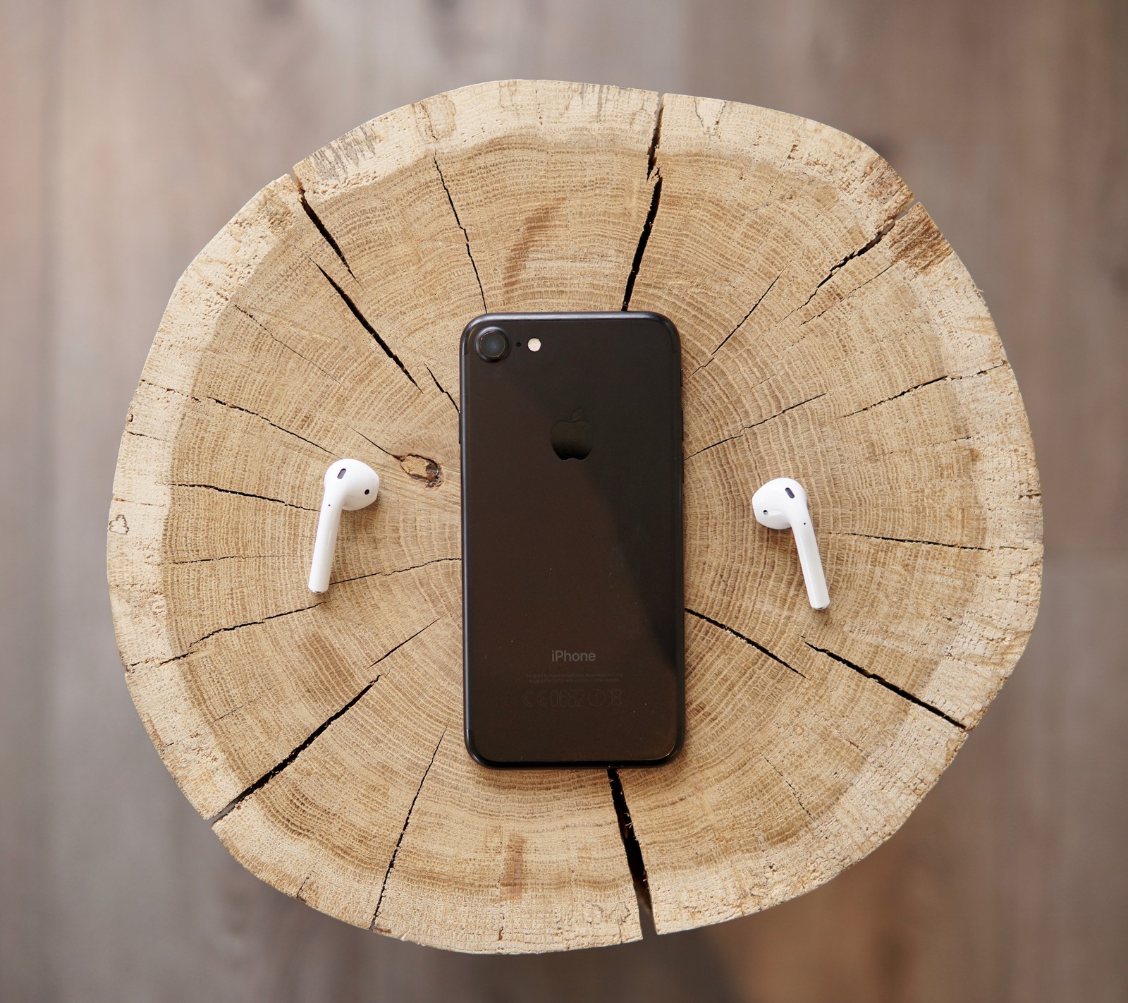 Un primer plano de un teléfono celular con auriculares sobre una mesa de madeira (2017, manzana, negro, black iphone7, iphone)