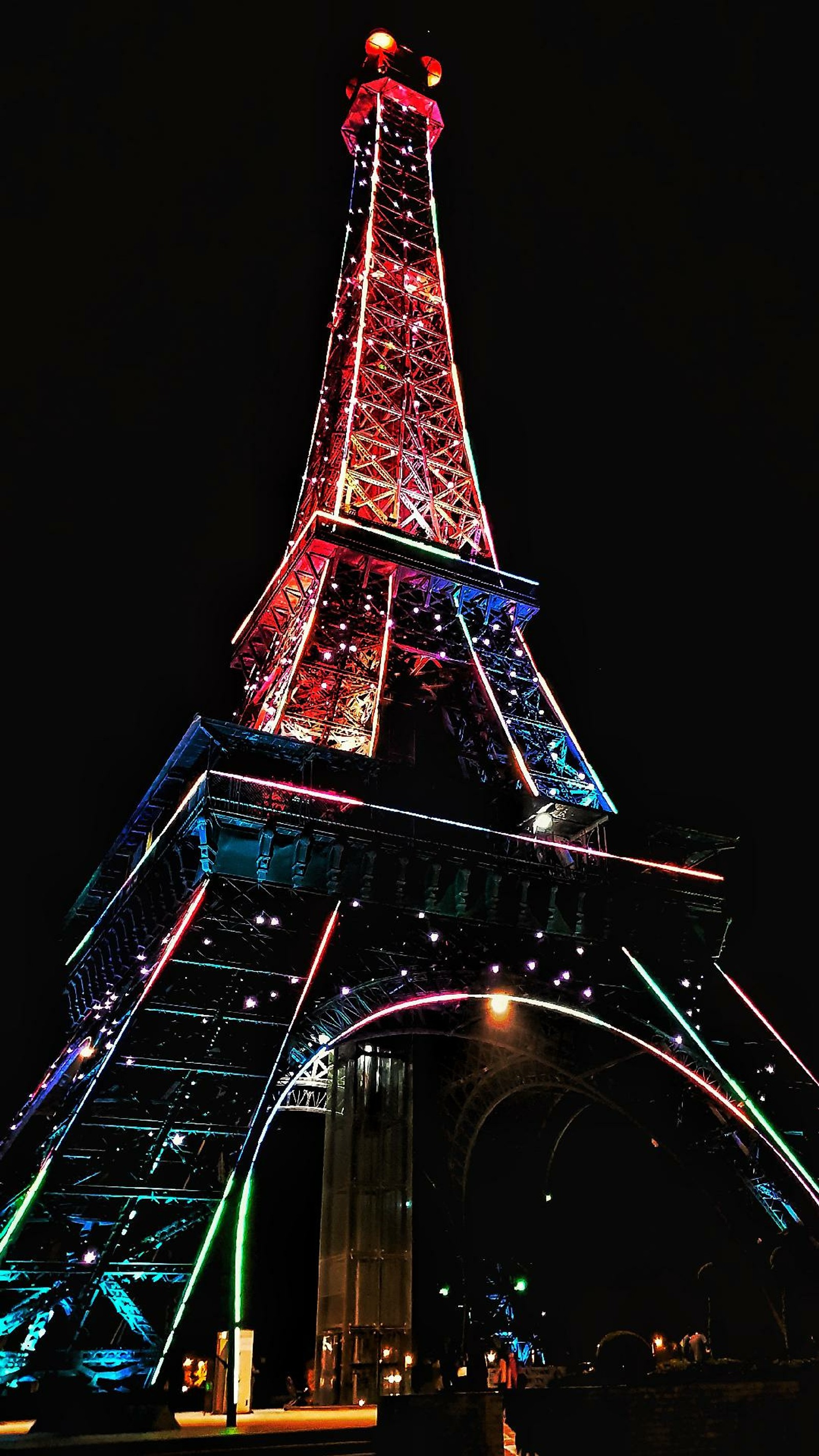 A torre eiffel iluminada com luzes coloridas à noite (paris, torre)