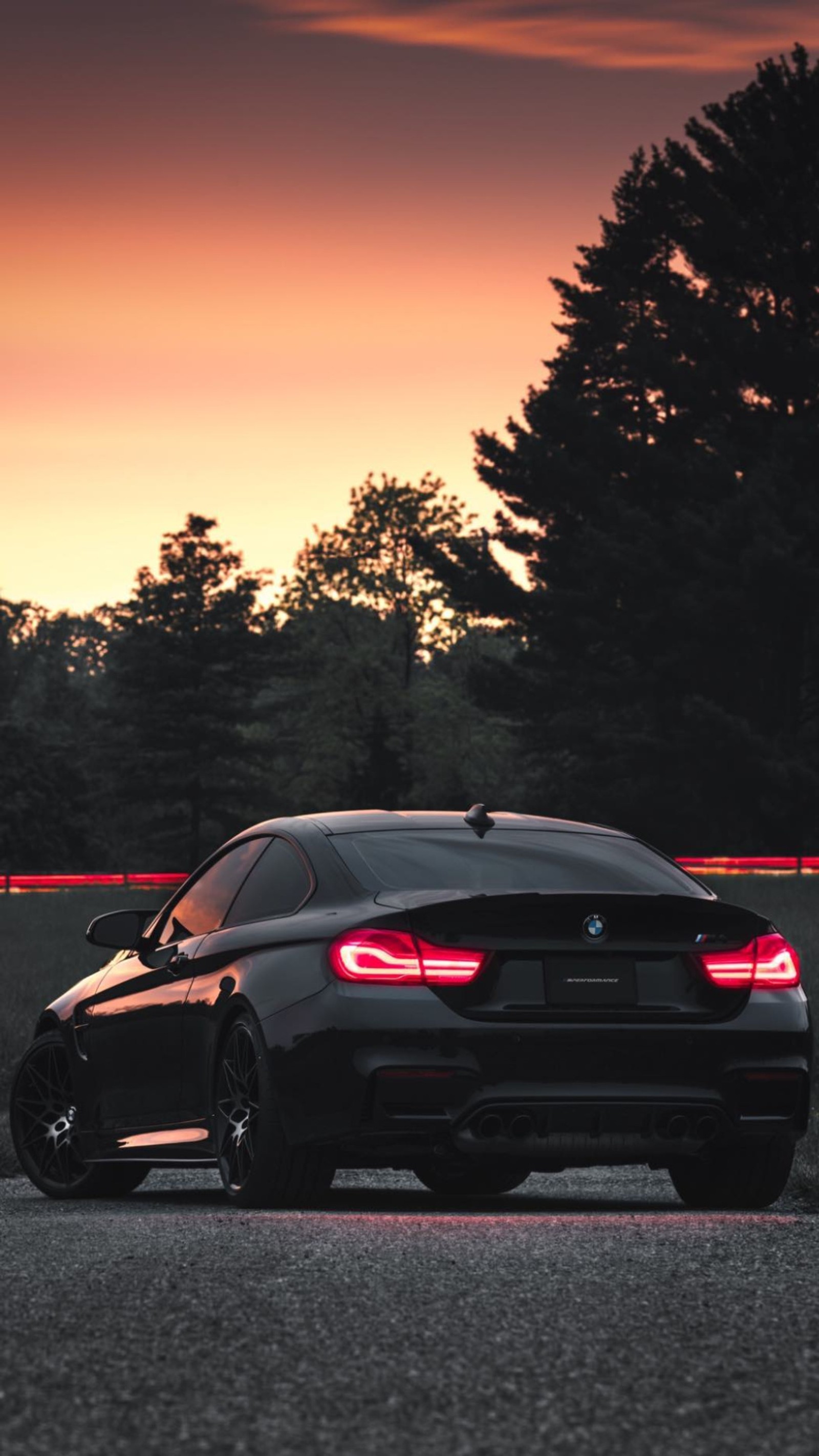 Primer plano de un coche negro conduciendo por una carretera al atardecer (bmw, m4, serie m, negro, luces)