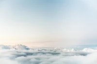 Nubes cúmulos sobre montañas brumosas bajo un cielo azul tranquilo