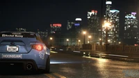 Subaru BRZ with Hoonigan livery parked on a city road at night, illuminated by vibrant city lights, showcasing the thrill of urban racing in "Need for Speed Payback.