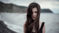 Mujer elegante con cabello largo castaño junto al mar