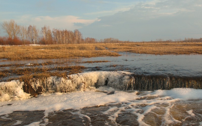 Протекающая вода через маленькую плотину в болоте (вода, банк, река, снег, замораживание)