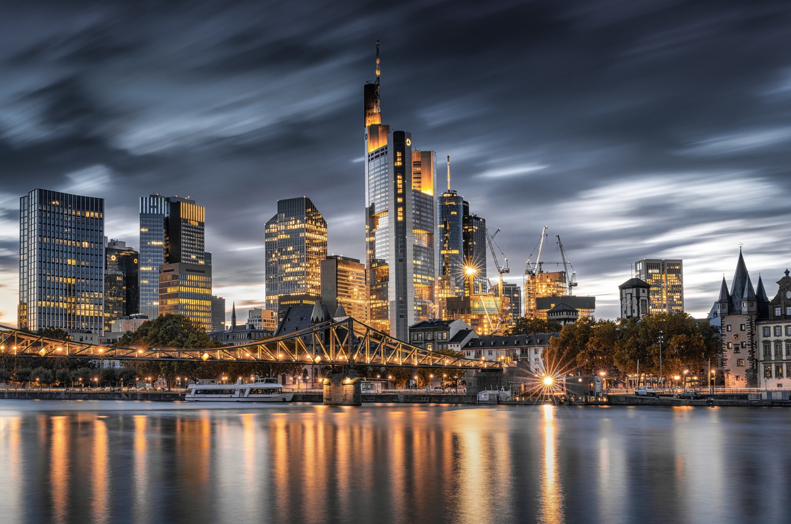 Vista árabe de um horizonte urbano com uma ponte e um barco (frankfurt, cidade noturna, alemanha, silhueta da cidade, iluminação)