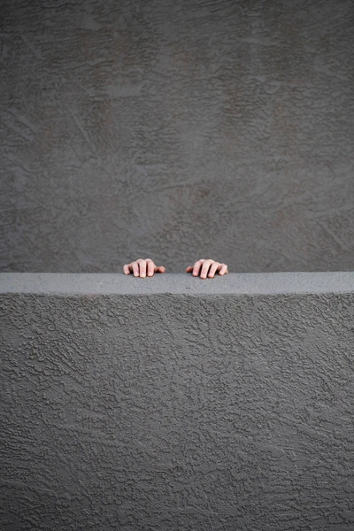 Mains émergeant d'un mur en béton texturé