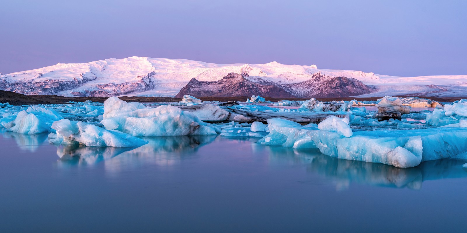 A close up of a body of water with icebergs in the background (jokulsarlon glacier lagoon, panorama, iceland, ultrawide, nature)