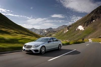 Mercedes-Benz S63 AMG cruising on a scenic mountain road.