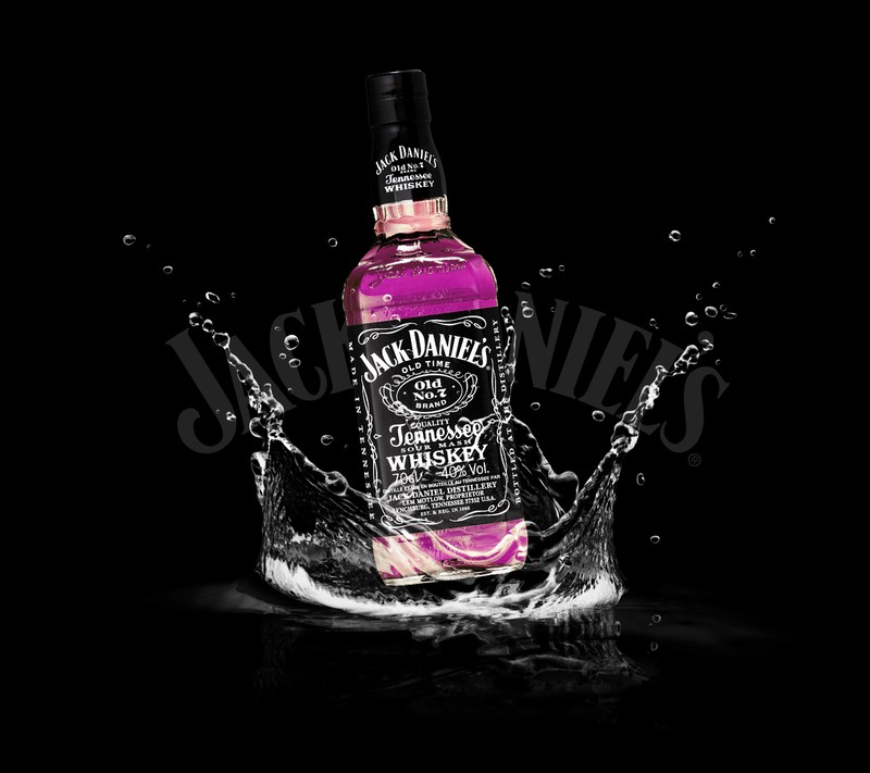 Крупный план бутылки jack daniels с розовой жидкостью и брызгами воды (америка, искусство, бренд, цвет, дэниелс)