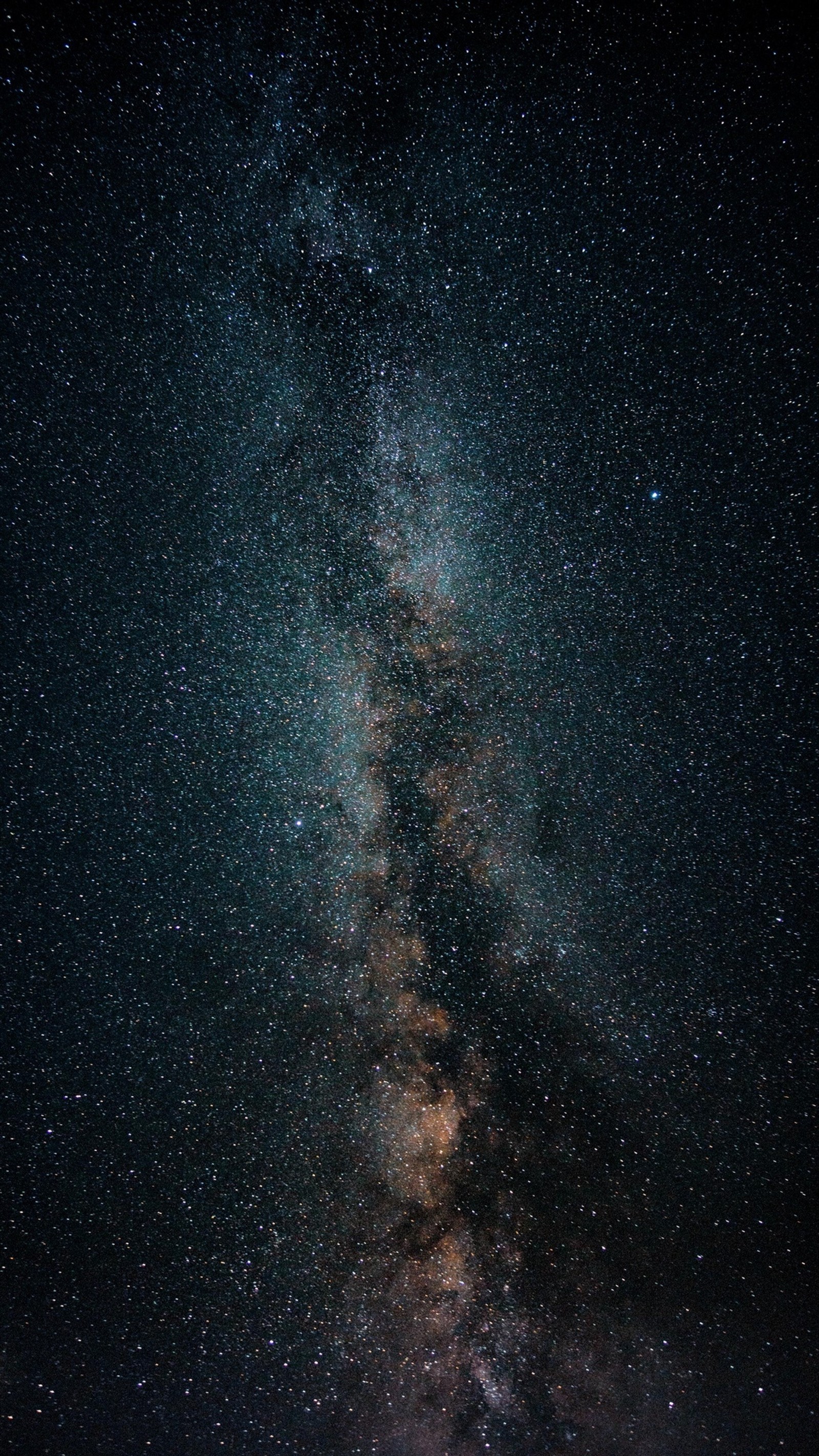 Um close de uma pessoa em pé na praia sob um céu noturno (galáxia, estrelas, noite, espaço, universo)