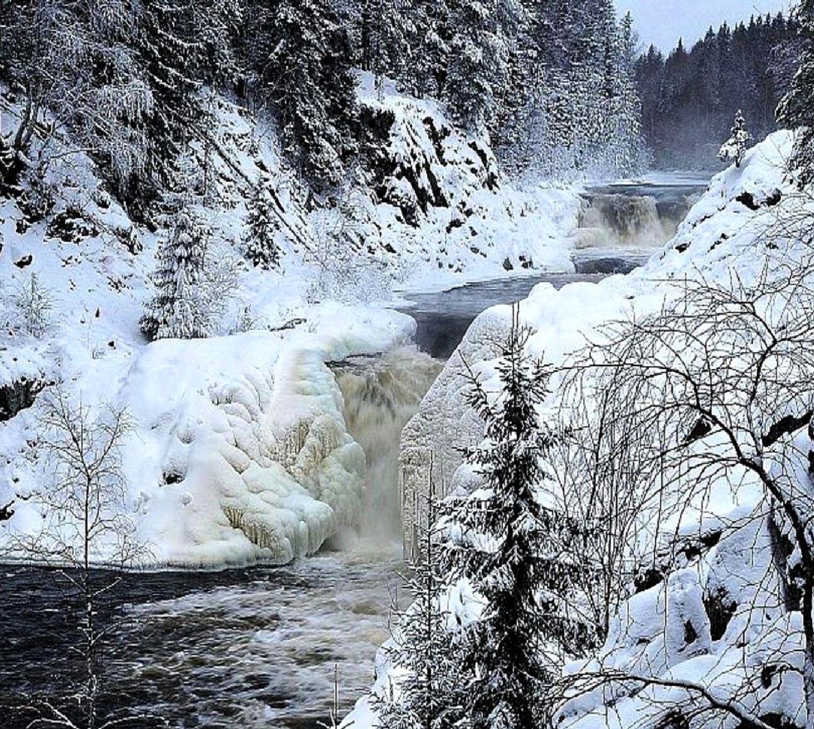 Snowy scene of a waterfall with snow and trees in the background (winter)