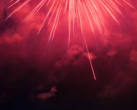 Des feux d'artifice vibrants rouges et roses illuminant le ciel nocturne