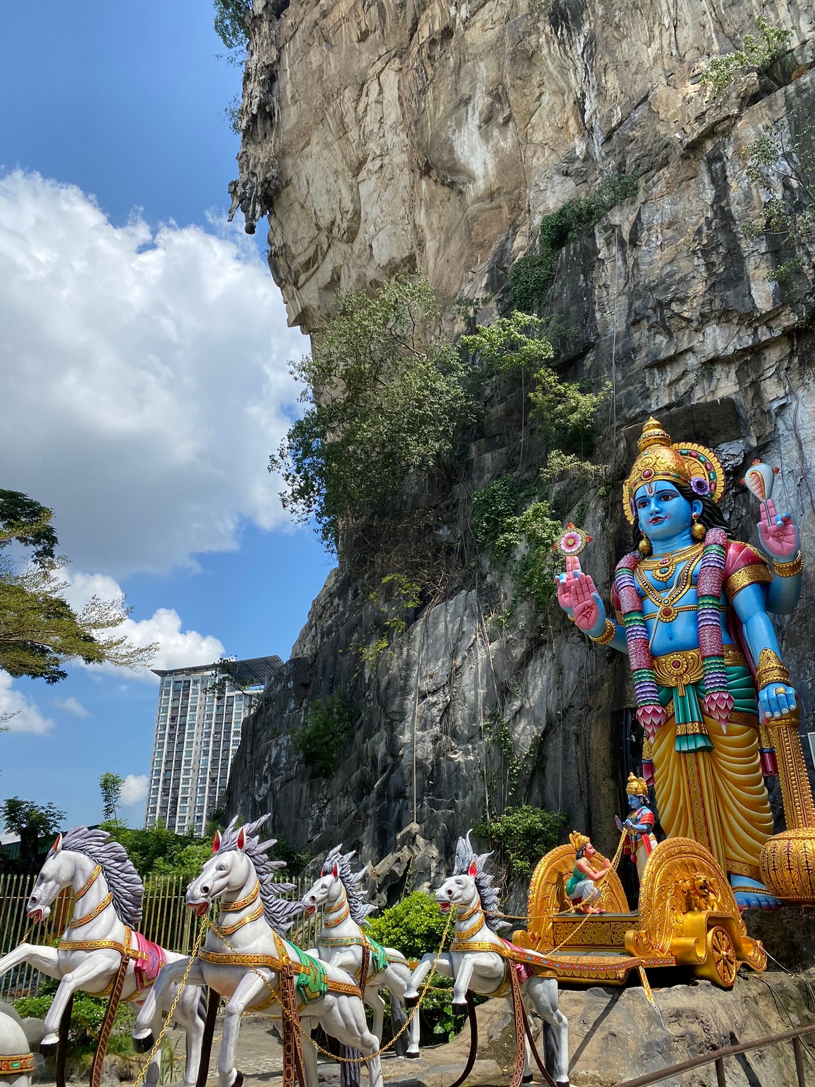 Estátua de um deus hindu com uma carruagem e cavalos em frente a uma montanha (turismo, atração turística, ciência, biologia, escultura)