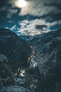 Mondbeschienenes Bergtal mit schneebedeckten Gipfeln und einem gewundenen Fluss