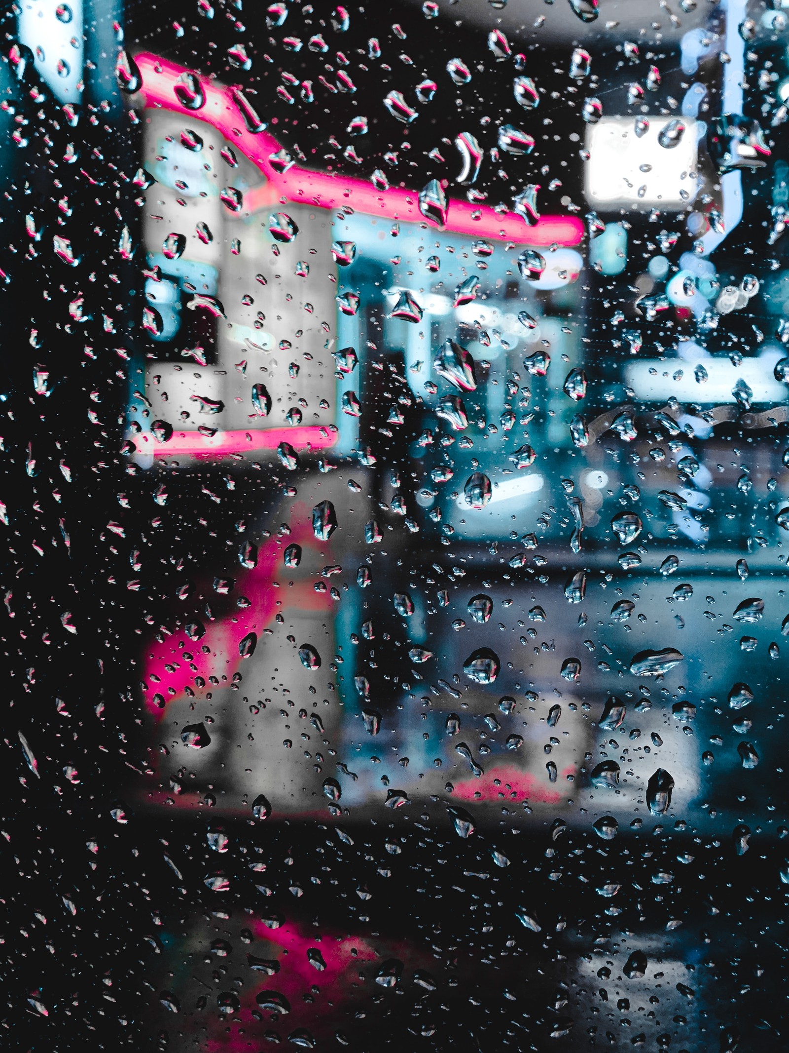 Um close de uma janela coberta de chuva com uma cidade ao fundo (água, azul, chuva, rosa, gota)