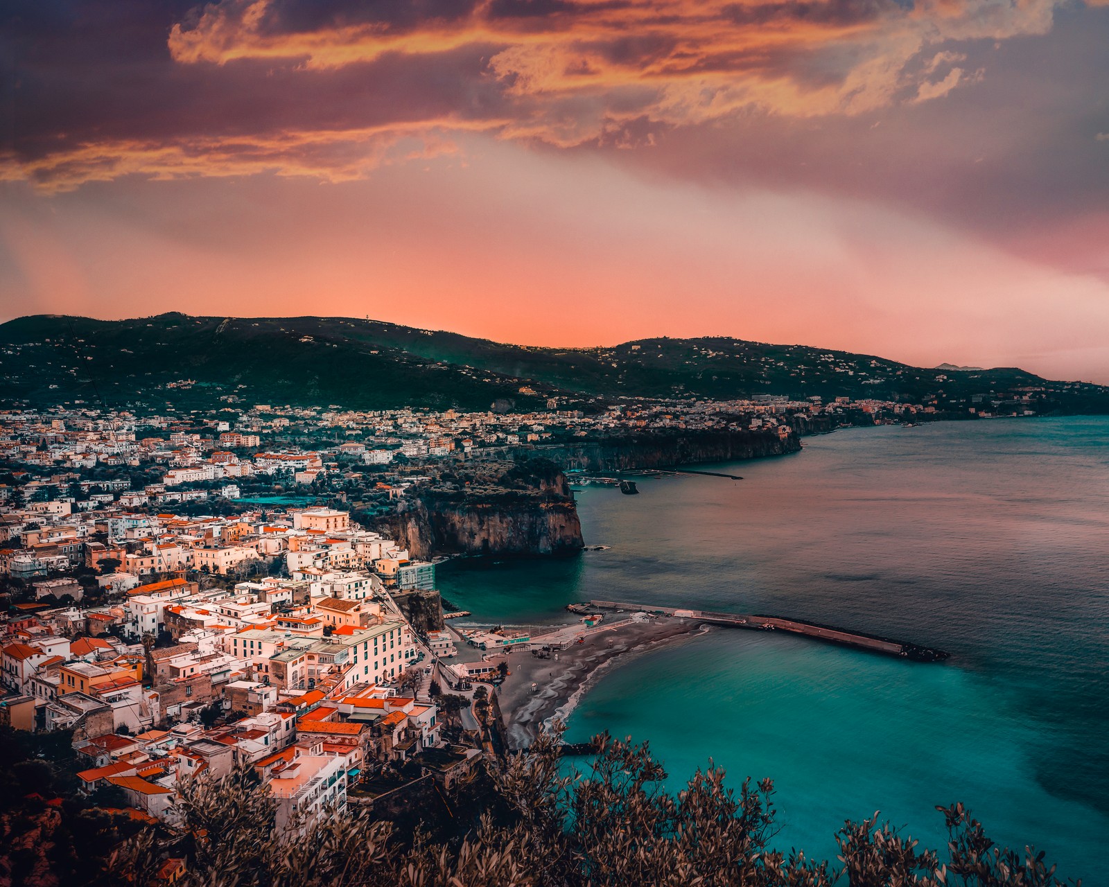 Vista de uma cidade na costa com um pôr do sol ao fundo (costa, baía, mar, corpo de água, natureza)