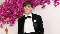 Cillian Murphy bei den Oscars vor einem lebhaften Blumenhintergrund.