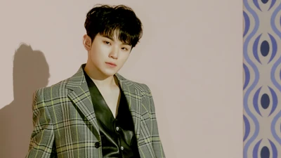 Woozi of Seventeen in stylish attire, exuding charisma against a pastel backdrop.