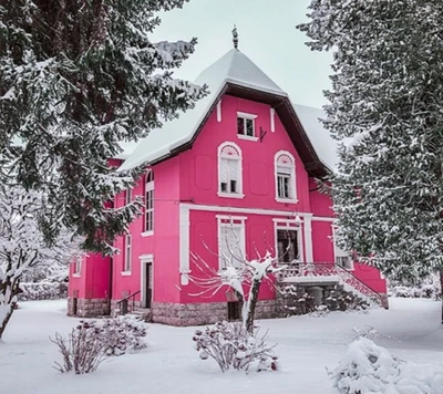 Encantadora casa rosa rodeada de un país de las maravillas invernal