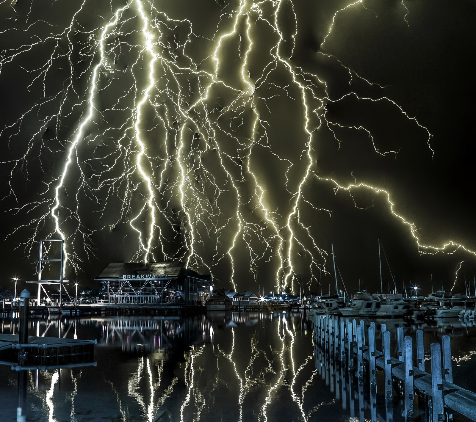 Un éclair frappe un port de plaisance la nuit avec des bateaux dans l'eau (éclair, nuit, tempête)