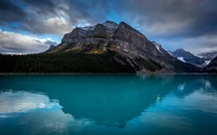 Serener blauer See mit Bergreflexion und bewölktem Himmel