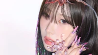 Giselle from Aespa showcases an ethereal look with intricate jellyfish-inspired accessories and striking nail art, merging fantasy with contemporary K-pop aesthetics.