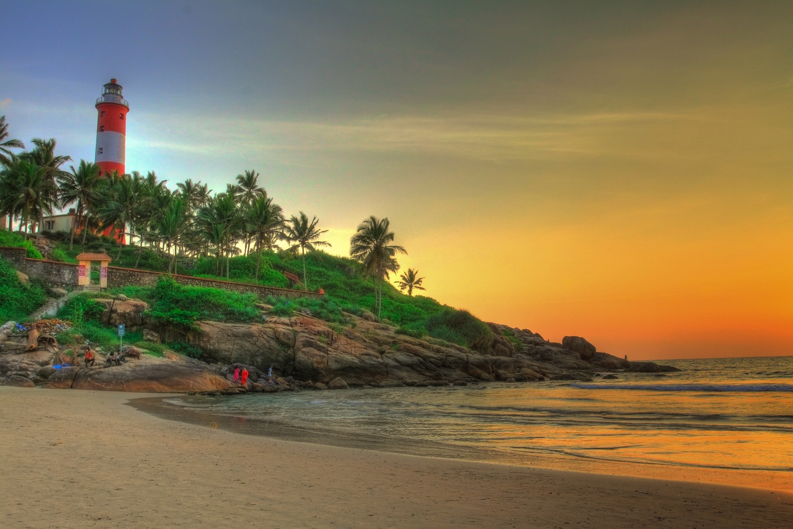 Vista de um farol em uma praia rochosa ao pôr do sol (praia, estância, costa, mar, oceano)