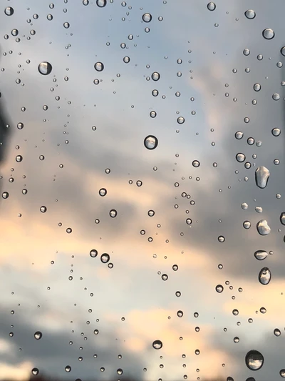 Regentropfen auf Glas reflektieren einen bunten Himmel