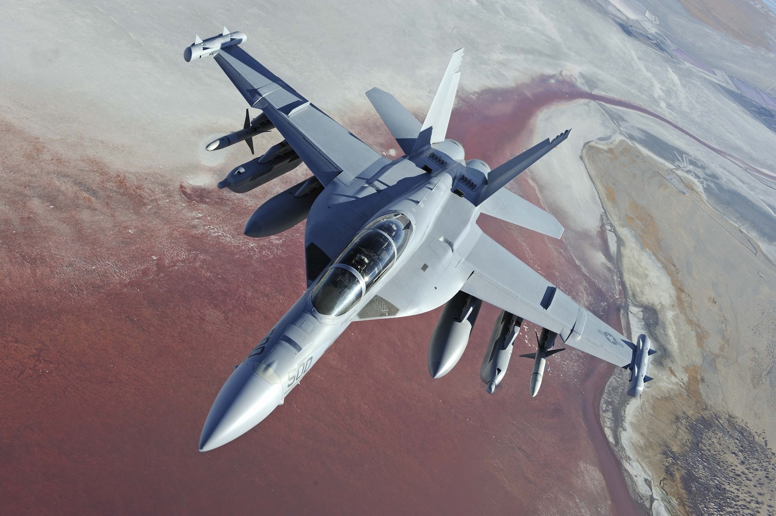 Arafed fighter jet flying over a desert area with a red sky (boeing f a 18e f super hornet, united states navy, military aircraft, aircraft, airplane)