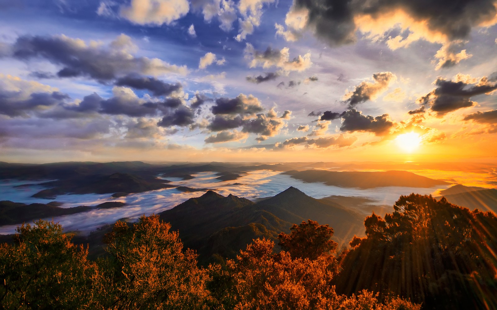 A view of the sun setting over the mountains and clouds (mount warning, australia, landscape, cloudy sky, sunset)