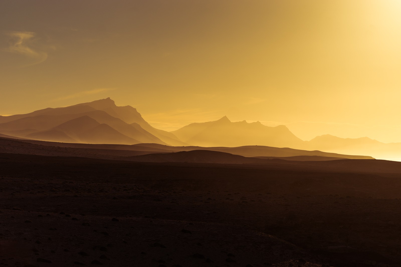 Montañas a lo lejos con un cielo amarillo y algunas nubes (montaña, crepúsculo, atardecer, resplandor, amanecer)