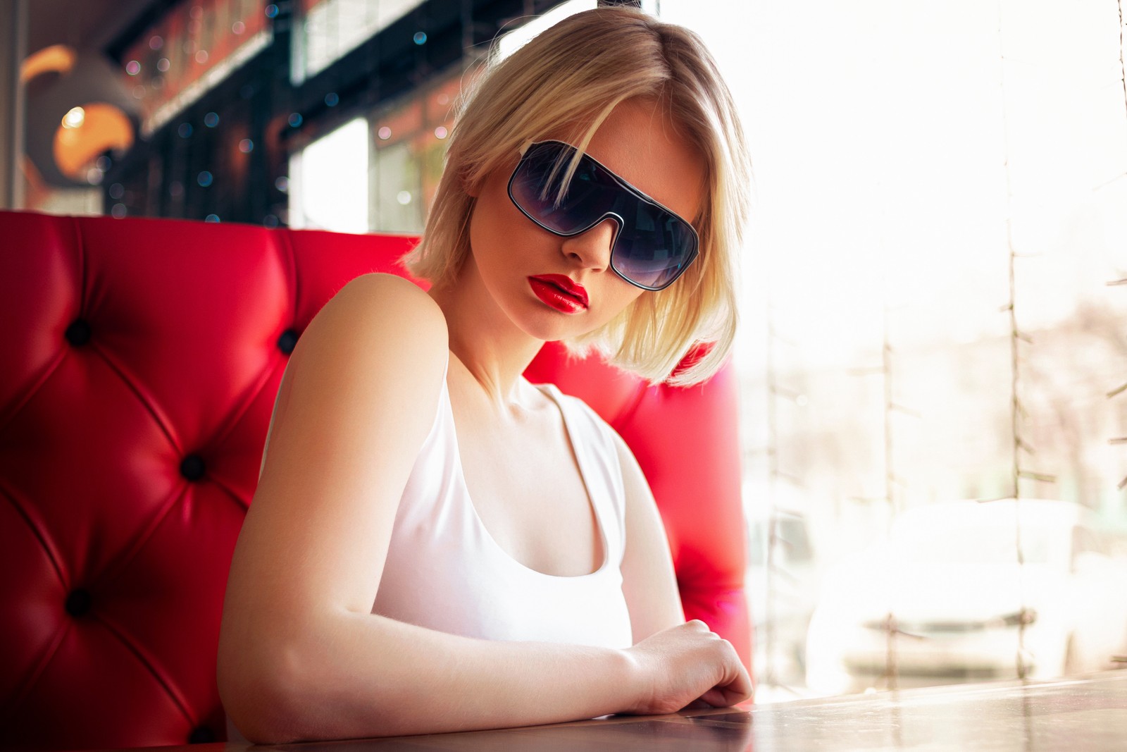 Blonde frau mit sonnenbrille sitzt an einem tisch in einem restaurant (frau, modern, teenager, lippen, schutzbrille)