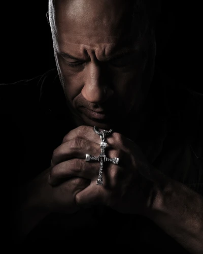 Dominic Toretto réfléchissant avec une croix dans un cadre sombre